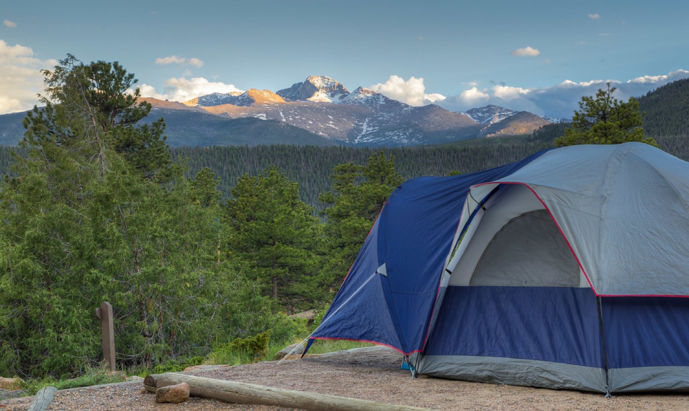 Technical fabric tent pitched outdoors against a mountain backdrop