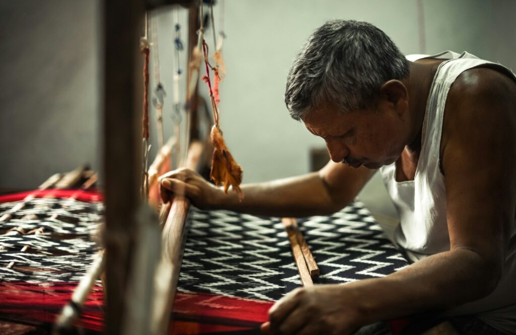 Weaver operating an industrial loom producing cotton and polyester cotton canvas fabric in India