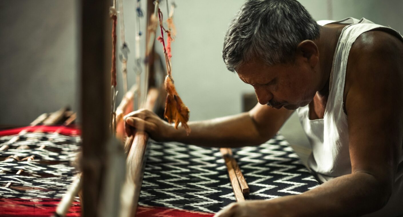 Weaver operating an industrial loom producing cotton and polyester cotton canvas fabric in India